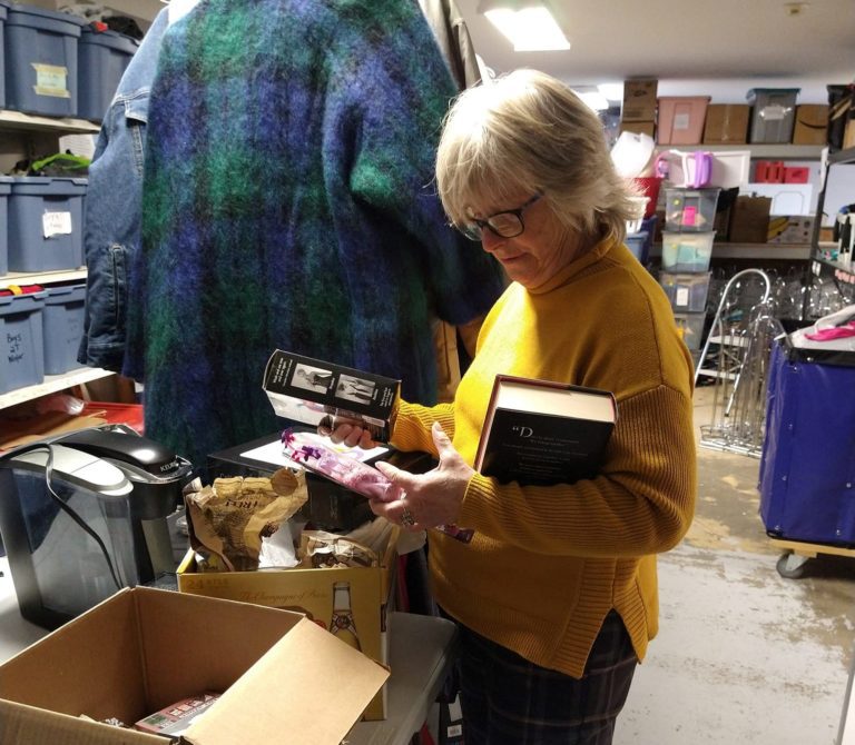 Senior Woman Looking At the Book and Other Bundles Inside the Donation Box