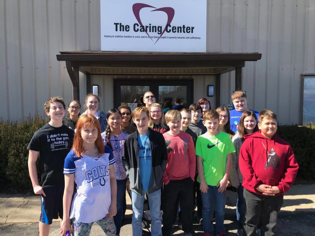 Bunch of Volunteer Children in Boone County Standing In front of The Caring Center Headquarter, Smiling Facing the Camera.