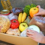 Donation box with food on old wooden background