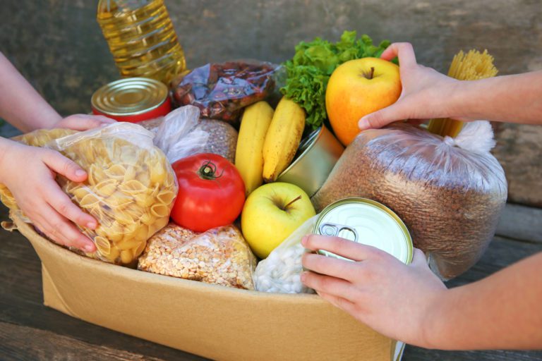 Donation box with food on old wooden background