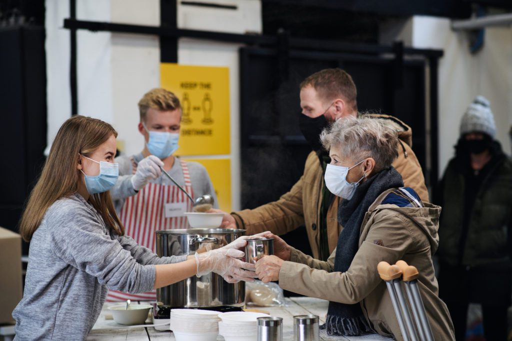 Volunteers Serving Hot Soup to Homeless Old Aged Woman
