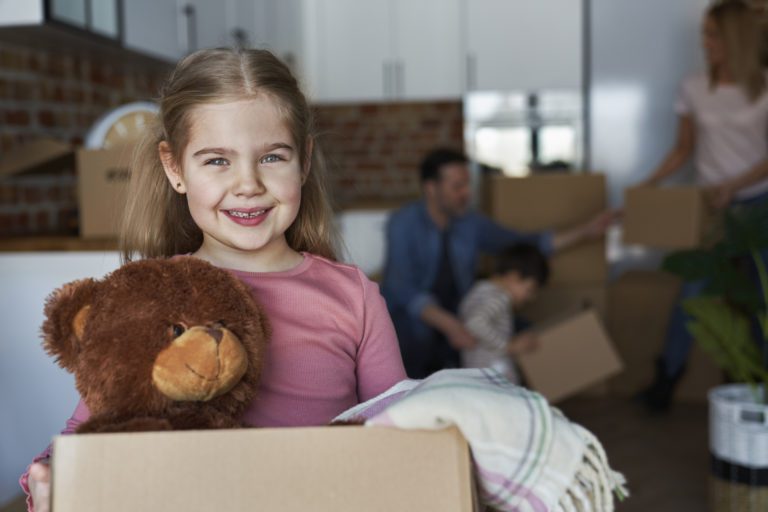 Portrait Of Little Girl Holding Cardboard Box With Teddy Bear