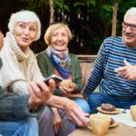 Group Of Cheerful Seniors Enjoying Time Together Drinking Tea Outdoors In Cafe And Sharing Life Stories
